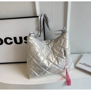 Close-up of holographic silver quilted bag with pink tassel and patterned shoulder strap