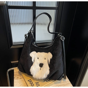 Detail of black corduroy shoulder bag featuring white schnauzer plush patch and silver buckle