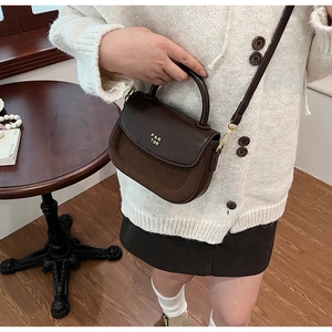 Detail of a dark brown patchwork crossbody bag with gold hardware and PAN TOR logo