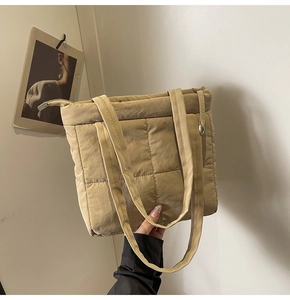 Close-up of beige quilted tote bag showing nylon texture and premium zipper detail