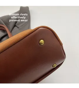 Detailaufnahme des Taschenbodens aus braunem Wildleder mit schützenden Goldnieten