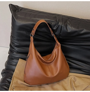 Detailansicht der braunen Hobo-Tasche aus Narbenleder mit Reißverschluss und breitem Gurt