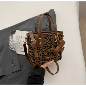 Gros plan du sac seau léopard avec bordure en cuir marron et breloque petit ours