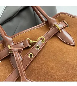 Detail der matten braunen Wildledertasche mit Goldbeschlägen und Lederbesatz