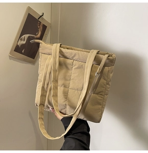 Close-up of beige quilted puffer shoulder bag with soft nylon finish and stitching detail