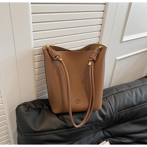 Detail of vintage brown pebble leather bucket bag with gold hardware and knotted strap