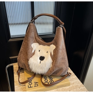 Close-up of brown corduroy tote bag with white plush dog applique and leather handle