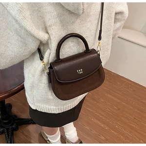Detail of dark brown mini handbag with PAN 'TOR logo and mixed leather texture finish
