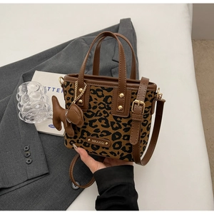 Détail du sac seau à imprimé léopard avec poignées en cuir marron et emblème
