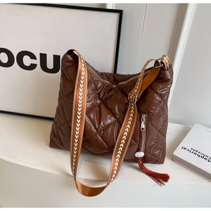 Close-up of brown quilted nylon shoulder bag with wide woven strap and red tassel