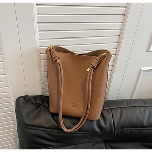 Close-up of brown pebbled leather bucket bag featuring unique knotted strap details