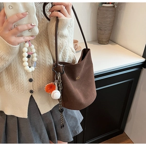 Braune matte Wildleder-Beuteltasche mit sportlichen Anhängern am Model getragen