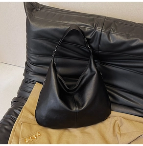 Detailansicht der schwarzen Lederstruktur und des breiten Schultergurts der Hobo-Tasche