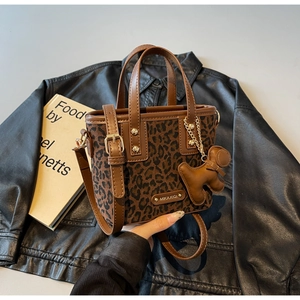 Détail du sac seau à imprimé léopard avec garniture en cuir marron et breloque chiot