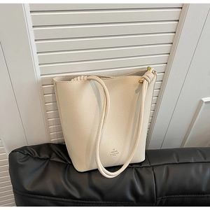 Detailed macro view of the cream bucket bag with metal bead strap and brand logo