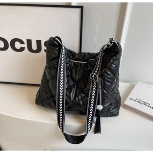 Detail of black quilted puffer tote bag with arrow pattern strap and tassel detail