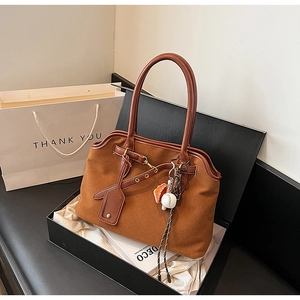 Close-up of brown suede tote bag with leather handles in a branded gift box setup