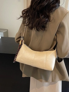 Beige matte leather underarm bag with smiley charm and woven strap details