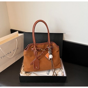 Detailed view of caramel suede tote bag with sports charms in premium gift box
