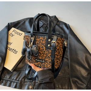 Détail du sac seau à imprimé léopard avec ferrures dorées et plaque de marque métal
