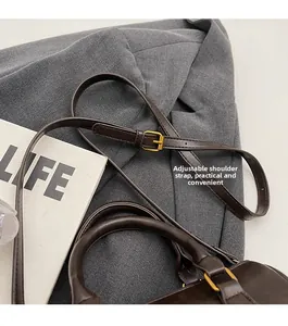 Detail of adjustable shoulder strap with gold buckle on dark brown leather pillow bag