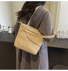 Detail of beige quilted shoulder bag with waterproof nylon texture on female model
