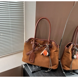 Detail of a brown textured tote bag with side eyelets and thin double handles