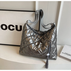 Detail of silver metallic quilted tote with woven shoulder strap and long tassel decoration