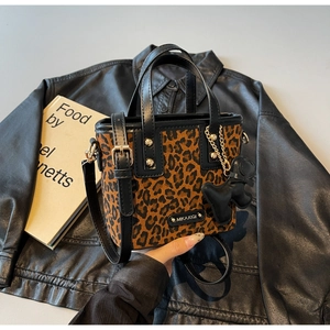 Détail du sac léopard avec pendentif en peluche noire et plaque de marque en métal