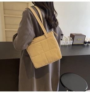 Quilted yellow shoulder bag with premium zipper detail worn by a model in a cafe
