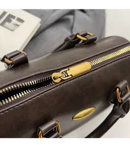 Detailed macro view of the smooth gold zipper and hardware on a brown Boston bag