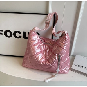 Macro detail of glossy quilted crossbody bag with stylish woven strap and tassel