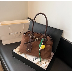 Brown frosted leather tote bag detail with decorative charms in a premium black gift box