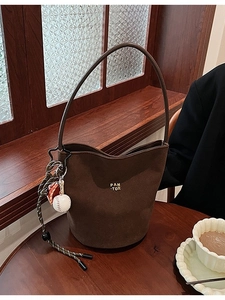 Braune Wildleder-Beuteltasche mit Sternschnalle und Baseball-Anhänger auf Holztisch