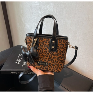 Détail du sac à main léopard avec rivets dorés et breloque en forme de petit chien