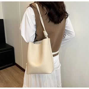 Detailed view of off-white lychee leather bucket bag with unique knotted strap design