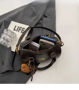Interior storage capacity of the dark brown Boston bag showing phones and plush bear charm