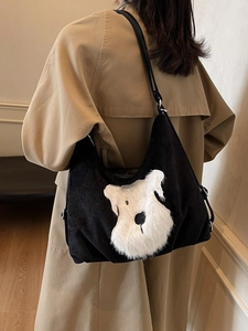 Large black corduroy hobo bag with schnauzer dog patch shown on shoulder in outdoor setting