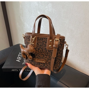 Détail d'un sac seau léopard avec breloque chiot et bandoulière réglable