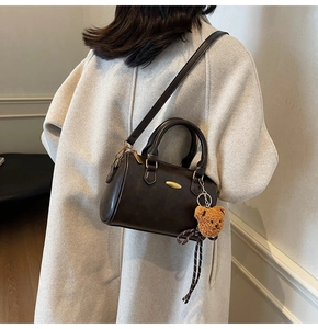 Deep brown Boston handbag featuring a retro teddy bear charm and gold metal logo detail