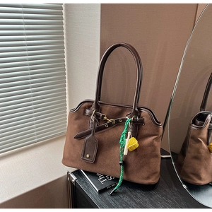 Detail of vintage brown tote bag with suede texture, polished handles and decorative charms
