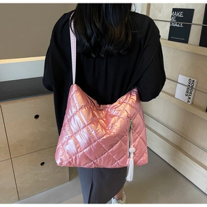 Metallic pink quilted hobo bag with tassel detail shown on model in modern library