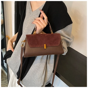 Detail view of burgundy suede and brown faux leather handbag with gold metal clasp