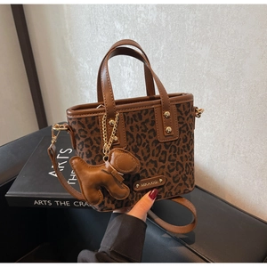 Détail du sac seau à motif léopard avec plaque dorée et breloque en cuir en forme de chien