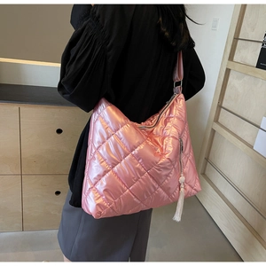 Pink quilted shoulder bag with glossy metallic finish and white tassel detail in close-up