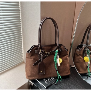 Braune Schultertasche aus Wildleder mit dunklem Lederbesatz und modischen Anhängern