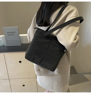 Detail of black quilted nylon tote bag showing soft padded texture and stitching