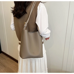 Detail of the knotted shoulder strap and textured leather finish on a gray bucket bag