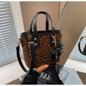 Détail du sac seau léopard avec finitions dorées et breloque noire élégante