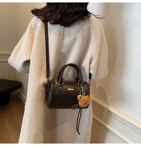 Brown Boston bag with teddy charm shown on a beige coat for a vintage commute style